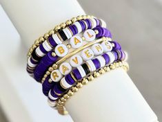 Purple, Black, White & Gold Stackable Heishi Polymer Clay Bracelet(s.)  Perfect for game days!  Bracelets are made with: 🤍Heishi beads 🤍18k gold filled spacer beads  🤍Gold plated brass spacer beads Some color shades may vary some.  EACH BRACELET SOLD SEPARATELY. STACK OPTIONS AVAILABLE.  Right colors, but wrong team? Message seller to customize yours with your favorite team, mascot or slogan.  INSTRUCTION: 1. Select wrist size from the drop down menu. Each bracelet is custom made to size. (Pl Nfl Clay Bead Bracelets, Keep Bracelet, Polymer Clay Bracelet, Sports Bracelet, Clay Bracelet, Stretchy Bracelets, Baltimore Ravens, Layered Bracelets, Purse Charms