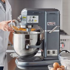 a person is pouring something into a large metal bowl on top of a countertop