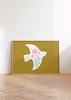 a bird with flowers on it is sitting in front of a white wall and wooden floor