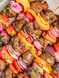 meat and vegetable kabobs on a white platter