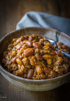 a bowl filled with chili and beans on top of a wooden table