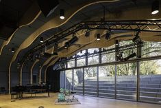 an empty stage with lots of lights and musical equipment on the floor in front of large windows