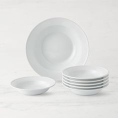 a stack of white plates sitting on top of a marble counter next to each other