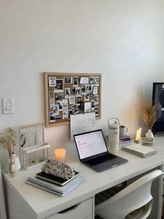 a laptop computer sitting on top of a white desk next to a cup and other items