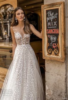 a woman standing in front of a sign wearing a wedding dress with flowers on it