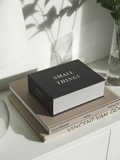 a stack of books sitting on top of each other next to a vase with flowers