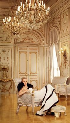 a woman laying on top of a white couch in a room with chandeliers