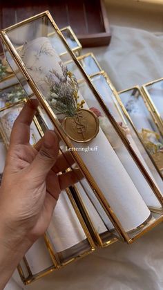 a person holding a piece of glass in front of some gold and white items on a table