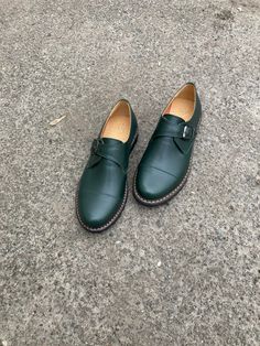 "Elevate your footwear game with our dark green monk strap shoes for women. These shoes feature a classic monk strap design, a soft natural leather upper, and a durable rubber sole for all-day comfort. Handcrafted with care, each pair is made from the finest materials to ensure both style and durability. The rich, dark green color of these monk strap shoes adds a unique touch to any outfit. The soft natural leather upper not only looks great but also ages beautifully over time, developing a unique patina that adds character and charm. Whether you're dressing up for a night out or running errands, these shoes are sure to make a statement. Don't settle for ordinary shoes when you can have the best. Add a pair of our dark green monk strap shoes to your collection today and step out in style a Workwear Monk Strap Slip-on Shoes With Rubber Sole, Green Wingtip Business Dress Shoes, Green Round Toe Oxfords For Work, Green Oxfords For Work With Round Toe, Green Leather Monk Strap Shoes With Leather Sole, Green Wingtip Oxfords With Rubber Sole, Classic Green Oxfords For Business, Workwear Dress Shoes With Tang Buckle, Green Slip-on Oxfords With Brogue Detailing