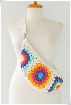 a white mannequin holding a multicolored crocheted bag on it's back