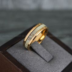 a gold ring with an antelope inlay inside it on top of a wooden box