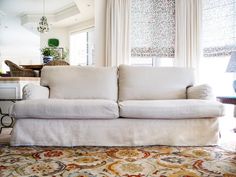 a white couch sitting on top of a rug in a living room next to a window