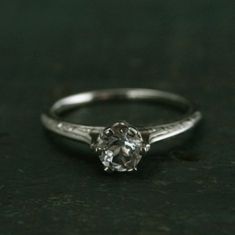 a close up of a ring on a black surface with a diamond in the center