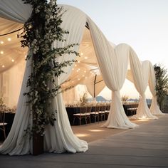 an outdoor wedding setup with white drapes and greenery