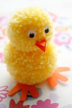 a small yellow toy chicken sitting on top of a flowered tablecloth covered table