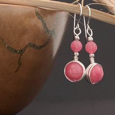 This unique pair of pink dangle earrings have handcrafted 924 Sterling Silver hooks, and are wire wrapped with bright silver plated wire to showcase pink rhodochrosite crystal gemstone. The earrings are fashioned to carry two rhodochrosite beads, a larger and a smaller one in each earring. The rhodochrosite has lovely consistent coral blush/ coral pink colour and is faintly mottled.  Drop length 3 cm Length from top of hook 4.5 cm width 1.2 cm For many other boho designs visit my Etsy shop at https://www.etsy.com/uk/shop/EarringsOfGemstone Postage and Packaging: Gift wrapping is available. While the default P&P option is set to Royal Mail 2nd class signed delivery (£1.50), an upgrade to Royal Mail 1st class signed delivery (£1.95) is available to select from the checkout basket before chec Pink Rose Quartz Hand Wrapped Jewelry, Hand Wrapped Rose Quartz Pink Jewelry, Hand Wrapped Pink Rose Quartz Jewelry, Pink Drop Earrings With Natural Stones, Pink Natural Stones Drop Earrings, Pink Natural Stone Drop Earrings, Pink Hand Wrapped Jewelry As Gift, Pink Sterling Silver Wire Wrapped Earrings, Pink Natural Stone Earrings For Gift