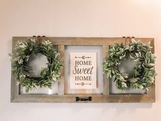 two framed wreaths are hanging on the wall next to a sign that says home sweet home