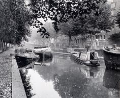 several boats are docked on the water in an old city street lined with trees and buildings