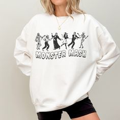 Rock this hauntingly cute Monster Mash Halloween crewneck sweathisrt! Featuring classic Halloween villains in a retro cartoon style, this sweatshirt is perfect for fans of spooky season, the Monster Mash, or anyone who wants a festive look with a touch of nostalgia. Stay spooky and grab yours today!  -50% Cotton 50% Polyester -Loose fit -Sewn in label -Runs true to size (size up for oversized fit) -Inclusive sizing: S-3XL All items are made-to-order: - We do not accept returns, size changes or cancellations. Please read size charts for these items. - Returns and exchanges are only available for damaged or wrong items. Retro Long Sleeve Halloween Tops, Funny Halloween Graphic Print Sweatshirt, Halloween Character Print Sweatshirt For Streetwear, Halloween White Screen Print Sweatshirt, Horror Themed Halloween Sweatshirt With Graphic Print, Halloween Band Merch Sweatshirt With Graphic Print, Halloween Horror Graphic Sweatshirt, Horror Graphic Print Sweatshirt For Halloween, Halloween Cotton Sweatshirt With Character Print