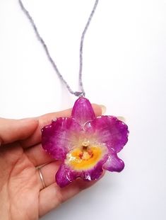 ☀️ Embrace the timeless beauty of orchids with this captivating handmade necklace! This exquisite necklace is more than just an accessory; it's a wearable work of art that captures the elegance and sophistication of orchids. Unlike traditional dried flowers, the orchid in this necklace is preserved in crystal-clear resin, ensuring its long-lasting beauty! Here's what makes this necklace truly special: Uniquely handcrafted: I cultivate and preserve the orchids myself, ensuring each necklace is a one-of-a-kind creation. You won't find another piece exactly like it! Even the flowers from the same orchid vary slightly in size and colour.  Timeless orchid design: The orchid's graceful silhouette and vibrant colors add a touch of sophistication and elegance to any outfit. Durable resin pendant: Dendrobium Orchid, Real Flower Necklace, Orchid Color, Dendrobium Orchids, Bridesmaid Gifts Jewelry, Jewelry Resin, Botanical Jewelry, Amethyst Beads, Flower Jewelry