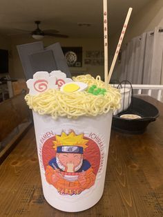 a cup filled with noodles and chopsticks on top of a wooden table