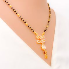 This 22k gold Mangal Sutra, weighing 9.9 grams, radiates festive charm with its stunning combination of black beads and cubic zirconia stones. The necklace measures 18" in length with a 1.5" drop, and adjustable 1" links offer a flexible fit. Finished in yellow gold, its hook lock ensures secure wear while adding to its elegance. Ideal for special occasions, this piece captures the perfect blend of tradition and sparkle, making it a dazzling addition to your jewelry collection. PRODUCT DETAILS Gold Purity(karat): 22k Item Weight(grams): 9.9 Item Finish: Yellow Gold Stone: Black Bead + Cubic Zirconia Necklace Length: 18" Drop Length: 1.5" Adjustable Links: 1" Links Lock Style: Hook Lock Elegant Black Temple Necklace As Gift, Elegant Black Temple Necklace Gift, Festive Black Necklace In 22k Gold, Black 22k Gold Necklace For Weddings, Black 22k Gold Jewelry As A Gift, Black 22k Gold Jewelry Gift, Black 22k Gold Jewelry For Wedding, Black 22k Gold Wedding Jewelry, Mangal Sutra