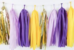 tissue tassels hanging on a string with gold, purple and yellow streamers