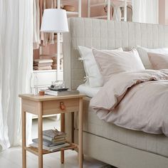 a bed with pink sheets and pillows in a bedroom