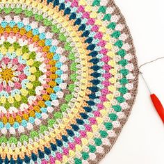 a crocheted doily with a red needle next to it