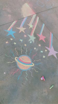 a chalk drawing on the ground with stars and a saturn drawn on it's side