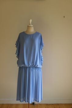 If you are looking for a gorgeous 20s style day dress then this is it!  beautiful lavish ruffles run down both sides of the dress adding feminine flair.  The drop waist and pleated skirt are a direct nod to the 20s!  A beautiful blue non crushable fabric will have you dancing the night, or day away!  An easy UK size 10 to 12 - the elasticed drop waist makes for a versatile fit.  Just add long beads, a headband or hat, and your ready to go! Evening Pleated Dress With Tiered Skirt, Party Dress With Pleated Waist And Tiered Skirt, Tiered Skirt Dress With Pleated Waist For Party, Vintage Flowy Dress With Ruffle Hem, Elegant Dress With Ruffled Skirt And Flutter Sleeves, Elegant Ruffled Skirt Dress With Flutter Sleeves, Elegant Tiered Pleated Ruffle Dress, Elegant Pleated Tiered Ruffle Dress, Flowy Tiered Dress With Accordion Pleats