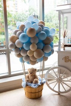 a teddy bear sitting in a basket with balloons