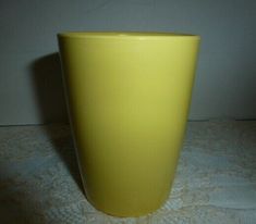 a yellow vase sitting on top of a white tablecloth covered floor next to a wall