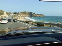 cars driving down the road next to the ocean