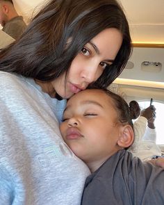 a woman holding a child in her arms while sitting on the back of an airplane