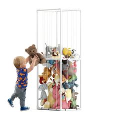 a little boy playing with stuffed animals in a cage