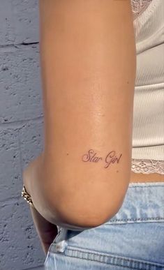 a woman with a small tattoo on her lower back and the words star girl written in cursive font