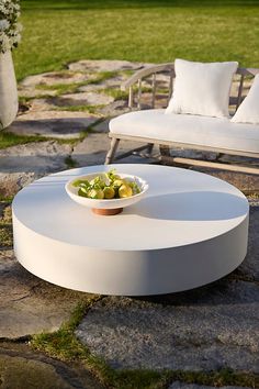 a bowl of fruit on top of a table in the middle of a stone patio