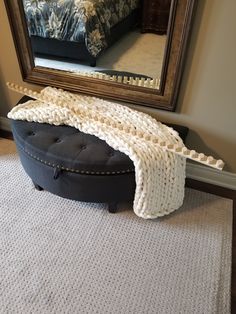 a black ottoman sitting on top of a carpet next to a mirror