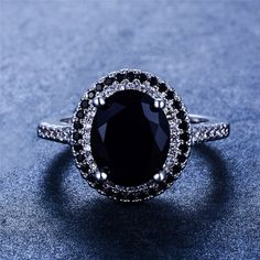 a black and white diamond ring sitting on top of a blue surface with diamonds around it