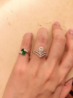 a woman's hand with two rings on it and an emerald in the middle