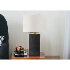 a table with a lamp on top of it next to a black chair and pillow