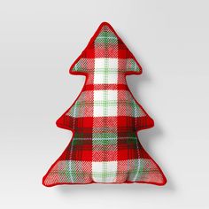 a red and green plaid christmas tree pillow on a white wall with a gray background