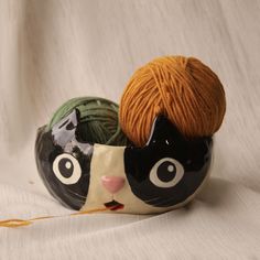 a black and white cat sitting on top of a ball of yarn