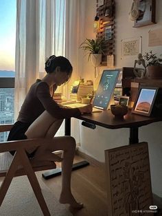 a woman sitting at a desk with a laptop computer on her lap and an ipad in front of her