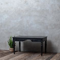 a small black table sitting on top of a wooden floor next to a potted plant