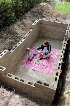 two people are sitting on a pink blanket in the middle of a cinder block structure