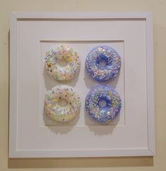 three framed doughnuts with sprinkles on them in a white frame