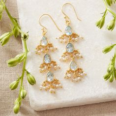 These stunningly bright pale Blue Topaz and Beaded Seed Pearl 18K Gold plated drop earrings are exquisitely crafted. The 3 teardrop shaped Blue Topaz gemstones are beautifully set in 18K gold over Sterling Silver and seed pearl beads surround each  gemstone. There are 3 stones in each earring as well as 2 seed pearl beads on either side of each gemstone. The length of the earrings help to elongate the neck and also create movement while wearing.  Blue Topaz are the birthstone for those born in December, making these a perfect birthstone gift. Blue Topaz are also associated with the 4th year of marriage, making these a great anniversary gift as well.  Blue Topaz are semi-precious gemstones and have been used to symbolise many positive attributes for centuries. Blue Topaz are most often a sy Festive Wedding Jewelry With Gemstone Accents, Wedding Dangle Chandelier Earrings With Gemstone Accents, Wedding Chandelier Earrings With Gemstone Accents, Teardrop Gemstone Chandelier Earrings For Wedding, Wedding Gemstone Drop Chandelier Earrings, Gemstone Dangle Chandelier Earrings For Wedding, Wedding Chandelier Dangle Earrings With Gemstones, Wedding Chandelier Earrings With Gemstones, Wedding Dangle Earrings With Gemstone Accents