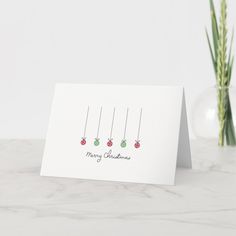 a white card with three christmas ornaments hanging from it